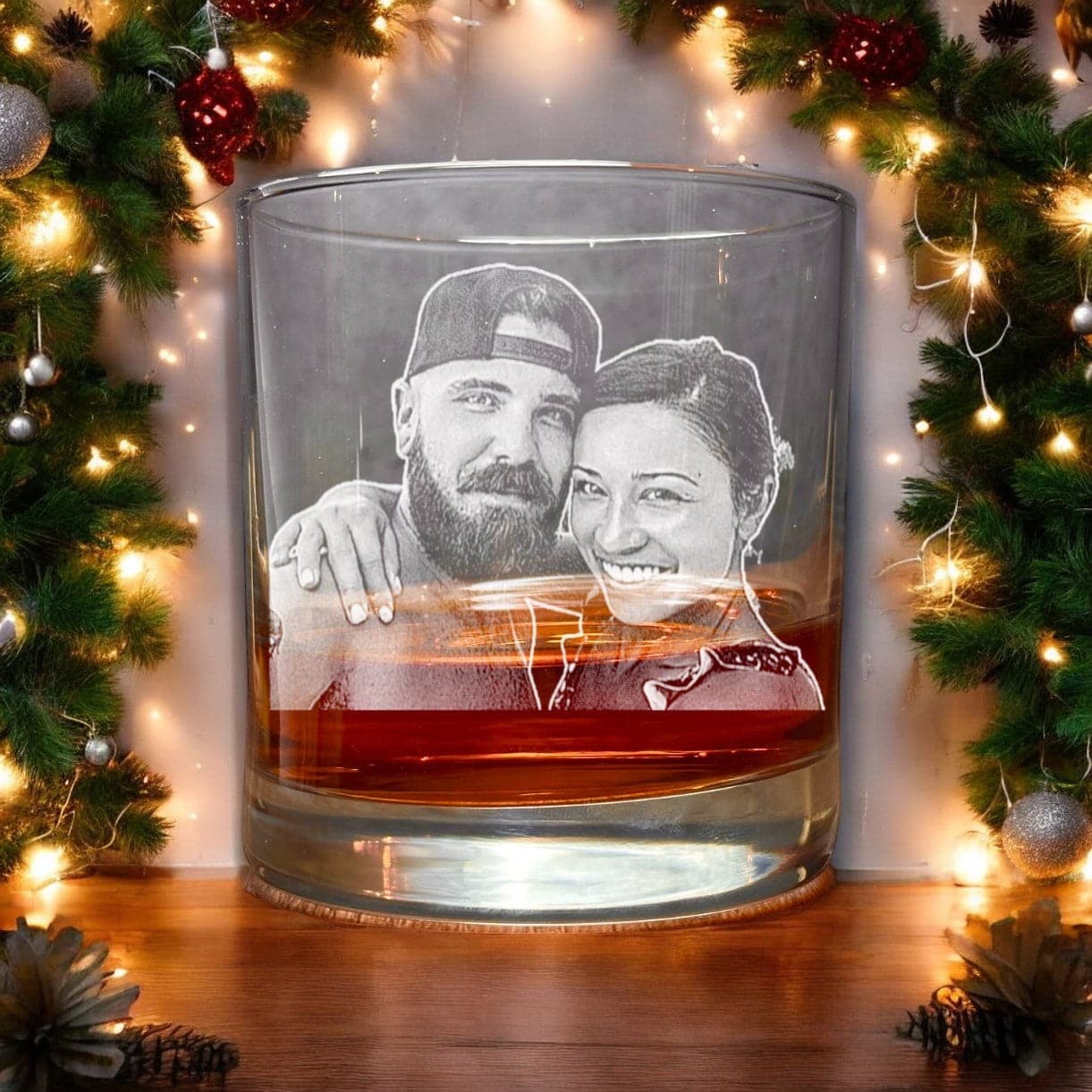 Surrounded by festive greenery and warm string lights, the "Your Photo Scotch Bourbon Glass - 11oz Personalized Father's Christmas Gift" from My Store features a custom photo engraving of a couple, creating a cozy holiday ambiance. It's the perfect personalized gift for whiskey lovers this Father's Christmas.